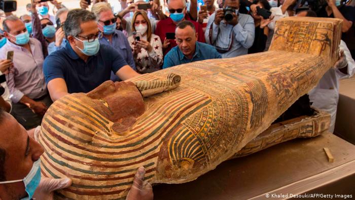 A picture taken on October 3, 2020, showing the Egyptian Minister of Tourism and Antiquities Khaled Al-Anani (left) and Mustafa Waziri (Deem), Secretary-General of the Supreme Council of Antiquities in Egypt, while opening a coffin excavated by the archaeological mission.  An Egyptian woman works at the Sakara Cemetery, 30 km south of the capital, Cairo.