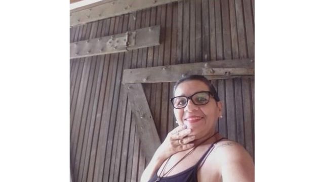 Severina smiles for a selfie in front of the wooden gate