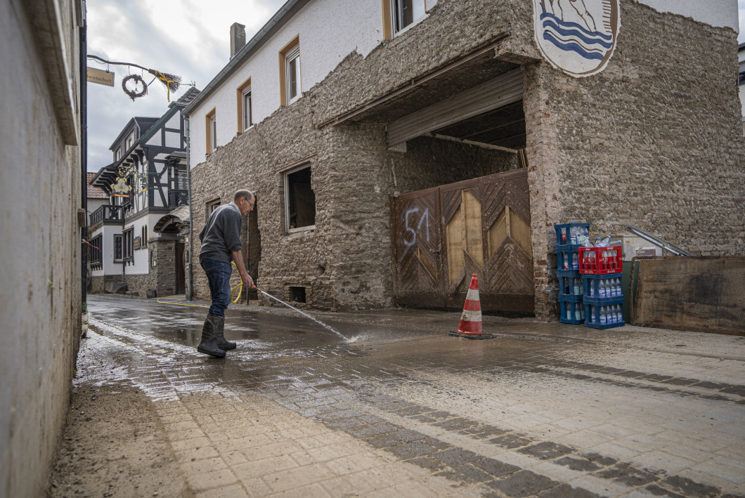 A man washes the streets of Dinau village.