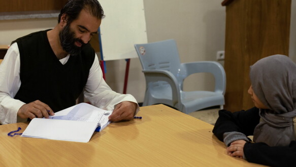 The director of the orphanage, Ahmed Khalil Mian, looks at a girl's schoolwork.