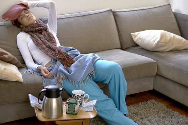Color photography.  A woman sitting on the sofa with her hand on her head, wearing cold clothes.