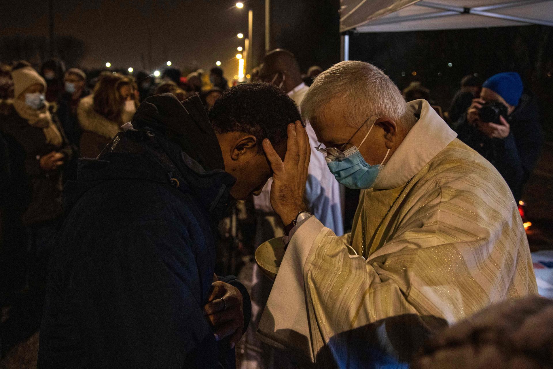 The Bishop of Aras, Mgr Olivier Leborgne, blesses a believer during a mass organized at a camp for the displaced in Calais (Pas-de-Calais) on Friday, December 24.