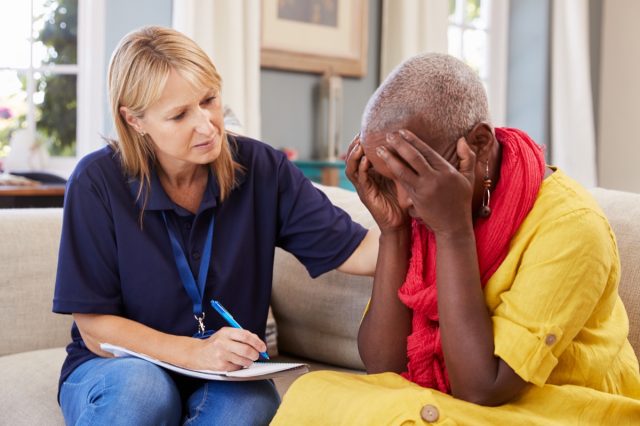 Mujer de mediana edad con pérdida de memoria, enfermedad de Alzheimer o demencia habla con su médico o enfermera en casa